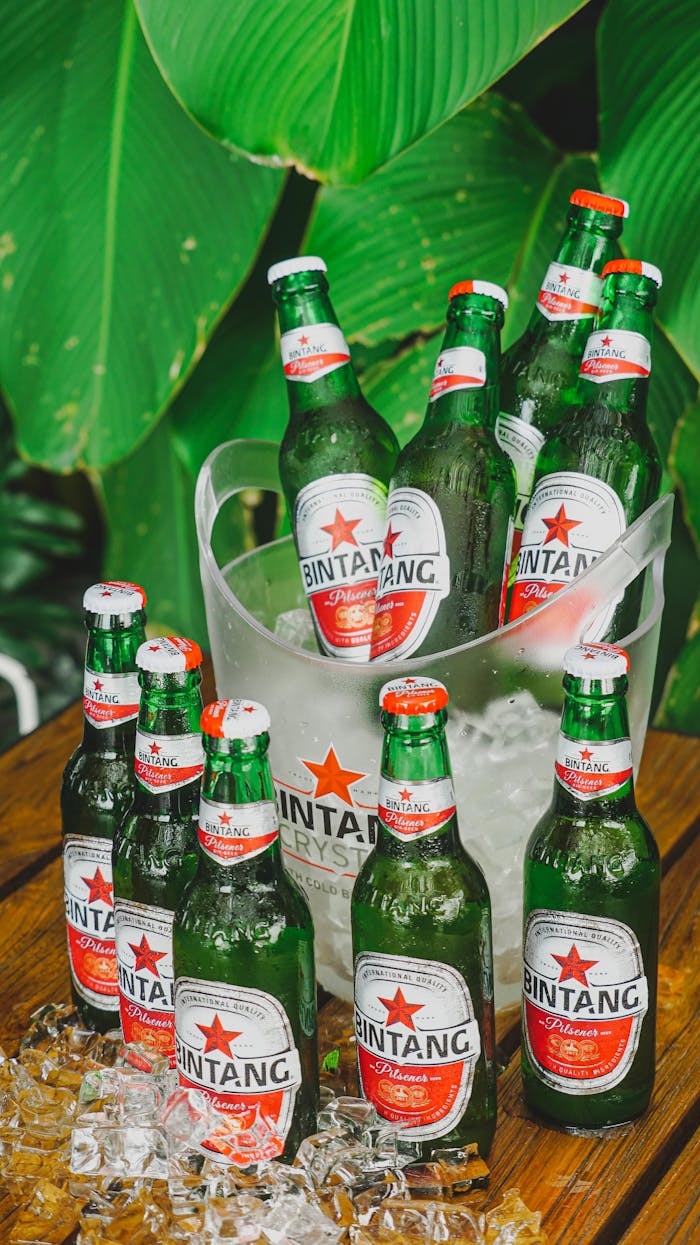 Chilled Bintang beer bottles in ice against lush greenery, perfect for tropical refreshment.